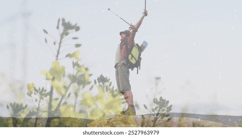 Caucasian male hiker raising walking poles in triumph on hill. Wearing a red shirt, shorts, and a hat, with a backpack and water bottle - Powered by Shutterstock