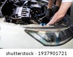 Caucasian male mechanic repairs car in garage. Car maintenance and auto service garage concept. Closeup hand and spanner.