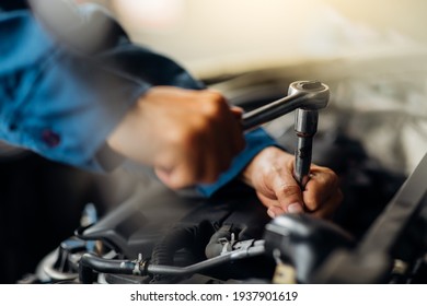 Caucasian male mechanic repairs car in garage. Car maintenance and auto service garage concept. Close up mechanical hand and spanner. - Shutterstock ID 1937901619