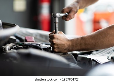 Caucasian male mechanic repairs car in garage. Car maintenance and auto service garage concept. Closeup hand and spanner.