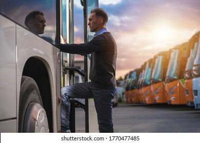 Caucasian Male Passenger in His 40s Getting Into Public Shuttle Bus on the Bus Station. Many Coaches Parked in Background.