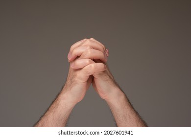 Caucasian Male Praying Hands. Close Up Studio Shot, Isolated On Brown Background.