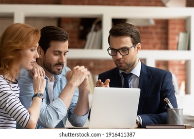 Caucasian Male Real Estate Agent Or Broker Consult Couple Clients Show Project On Laptop Screen. Man Realtor Or Financial Advisor Talk Have Consultation With Spouses At Office Meeting. Rental Concept.