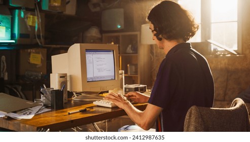 Caucasian Male Software Engineer Programming on Old Desktop Computer In Retro Garage. Focused Man Starting Fintech Startup Company In Nineties. Coding Innovative Online Service At Home.