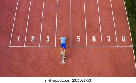 Caucasian male sprint runner alone on the athletic track, taking starting position and running in line four, aerial above shot. - Shutterstock ID 2311021953