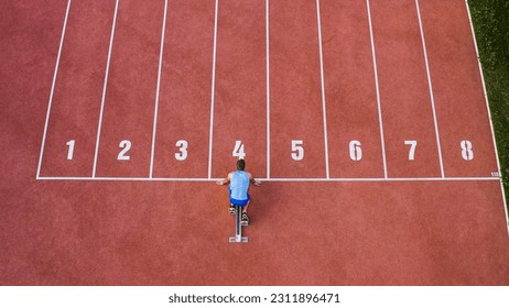 Caucasian male sprint runner alone on the athletic track, taking starting position and running in line four, aerial above shot. - Shutterstock ID 2311896471