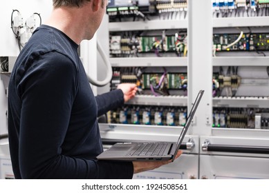 Caucasian Male Superyacht Engineer - ETO Working On The Engine Room Control Panel With Laptop