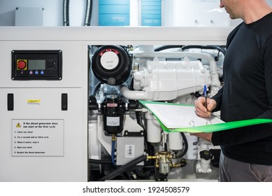 Caucasian Male Superyacht Engineer working on the engine room, inspecting the generator with checklist folder and pen in his hand