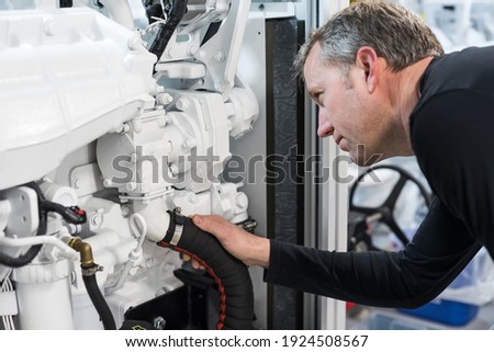 Caucasian Male Superyacht Engineer working on the engine room, inspecting the generator