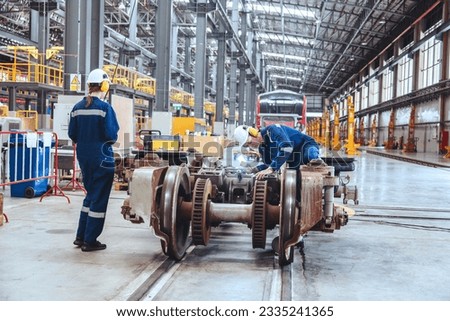 Caucasian male technician and female engineer wearing safety helmet uniform inspect electric train parts and maintenance railway in railway control maintenance station.