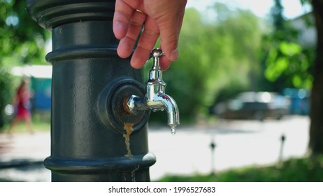 Caucasian Male Turning Off Water Dripping from Public Tap Faucet on Sunny Day to Save Water