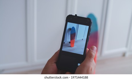 Caucasian Male Using Smartphone To Take Photo Of Skateboard To Sell It During Online Garage Sale To Earn Extra Money