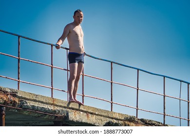 Caucasian Male Wants To Jump Into The Water From The Wharf. Aganist On Blue Sky. Sudak, Crimea - 4 October, 2020