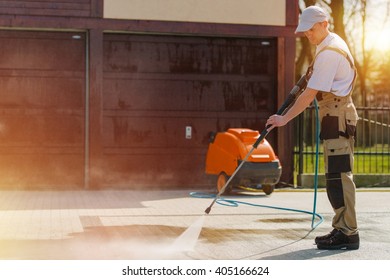 Caucasian Male At Work Cleaning Residential Brick Road Using High Pressure Water Cleaning System Machine