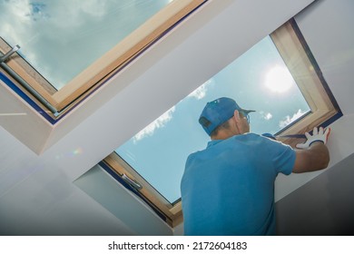 Caucasian Male Worker in Blue Outfit Preparing Skylight Window before Painting the Walls White in the Room. Renovation Work Theme.