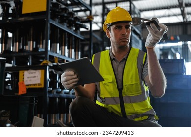 Caucasian male worker holding tablet with auto spare parts to check quality of workpieces in factory. - Shutterstock ID 2347209413