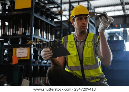 Caucasian male worker holding tablet with auto spare parts to check quality of workpieces in factory.