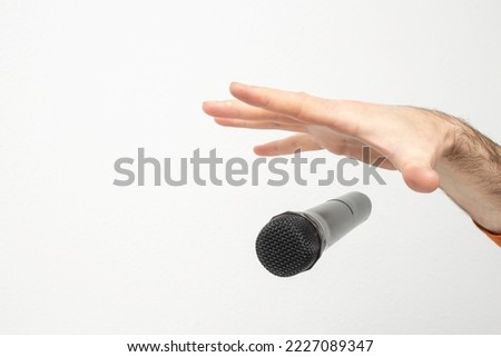 Caucasian male's hand dropping the mic, stretched hand and a microphone soft focus close up isolated on white background