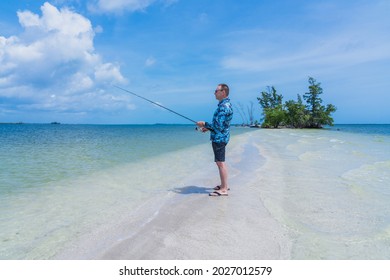 Caucasian Man 60 Years Old With A Fishing Rod In His Hands While Fishing In The Salt Water Of The Ocean On Indian River Island, Florida