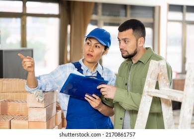 Caucasian Man Architect And Asian Woman Builder Discussing Project Documentation In Construction Site. Woman Poitning Finger.