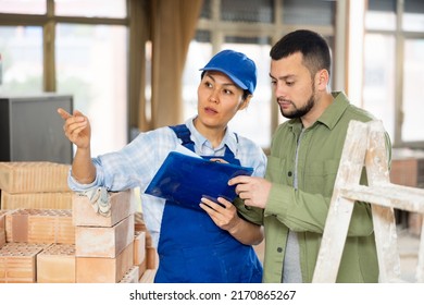 Caucasian Man Architect And Asian Woman Builder Discussing Project Documentation In Construction Site. Woman Poitning Finger.