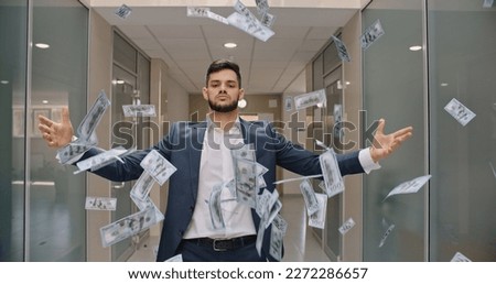 Caucasian man with arrogant face is standing in office hall throwing money in air, celebrating his success - way to success concept