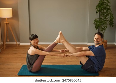 Caucasian man and Asian woman practicing yoga together in yoga studio - Powered by Shutterstock