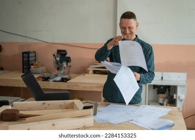 Caucasian man assembles furniture in the workshop and looks at the instructions.  - Powered by Shutterstock