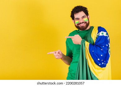 caucasian man with beard, brazilian, soccer fan from brazil, pointing left with finger, photo for advertisement, indication. - Powered by Shutterstock