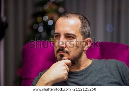 
Caucasian man with beard sitting on purple sofa with hand on chin Stok fotoğraf © 