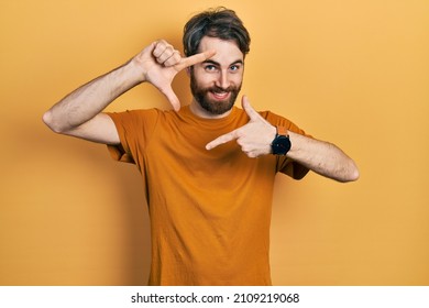 Caucasian Man With Beard Wearing Casual Yellow T Shirt Smiling Making Frame With Hands And Fingers With Happy Face. Creativity And Photography Concept. 