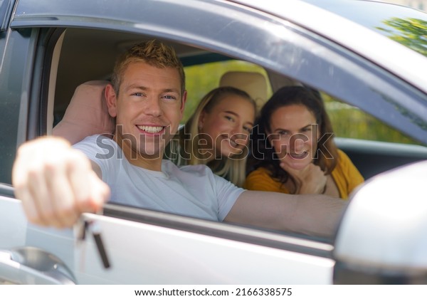 Caucasian man buying new or rent car and showing the\
key, sitting in car.