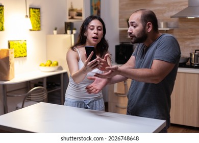 Caucasian Man Caught Cheating By Jealous Wife Looking At Secret Messages On Smartphone. Couple Fighting And Yelling Because Of Infidelity And Trust Issues. Marriage Crisis, Conflict