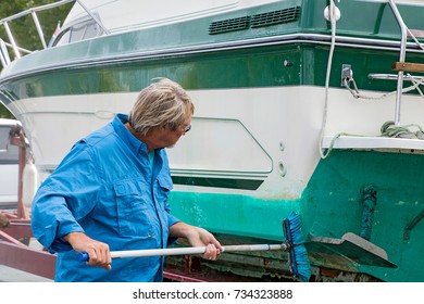 Caucasian Man Cleaning Boat Hull With Long Brush