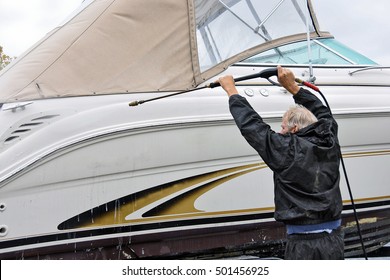 Caucasian man cleaning power boat hull with power washer