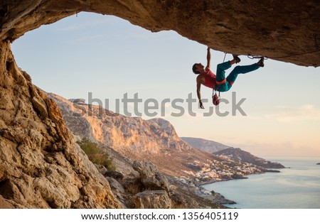 Caucasian man climbing challenging route in cave at sunset