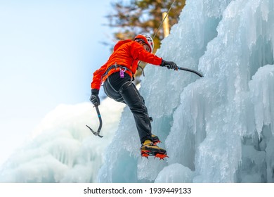 Caucasian man with climbing equipment, ice axes and rope, hiking at a frozen waterfall - Powered by Shutterstock