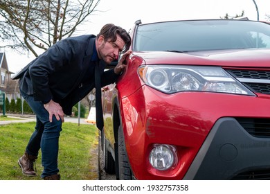 Caucasian Man Crouching Down And Inspecting A Car