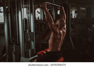 Caucasian man doing lat pull-downs on a machine. 