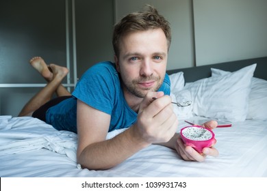 Caucasian Man Eating Dragon Fruit With Spoon In The Bed. He Has A Healthy Breakfast