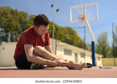 caucasian man with expression of pain on his face has been injured playing basketball. His ankle is swollen due to a sprain or broken bone. High quality photo