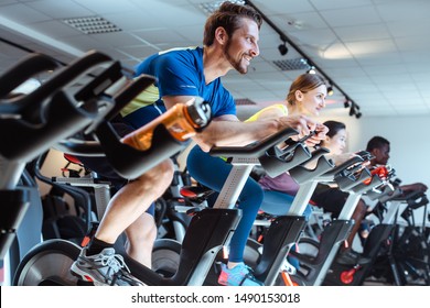 Caucasian man and friends on fitness bike in gym during workout - Powered by Shutterstock