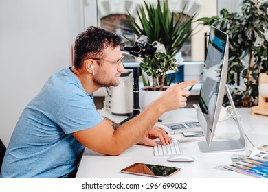 Caucasian Man With Glasses Poses Sitting At Table With Computer In Office