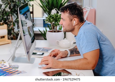 Caucasian Man With Glasses Poses Sitting At Table With Computer In Office