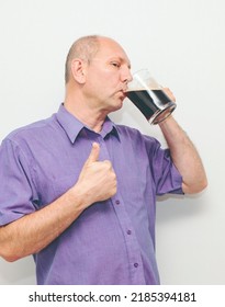 Caucasian Man Is Happy, Drinking Dark Beer From A Beer Mug.