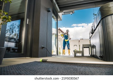 Caucasian Man In His 40s Cleaning Up The Outdoor Terrace Of His House Using Pressure Washer. Preparations Before The Start Of Summer Season. Home And Yard Maintenance Theme.