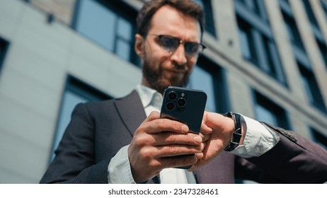 Caucasian man hold mobile phone outdoors busy nervous businessman check time at wristwatch texting message on smartphone stressed guy business entrepreneur office employer wait meeting in city outside - Powered by Shutterstock