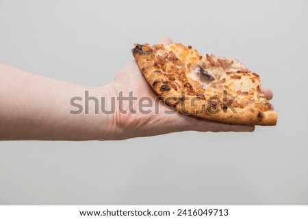 A Caucasian man holds a slice of pizza in a hand - white background behind.