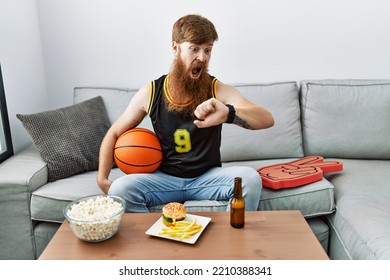 Caucasian man with long beard holding basketball ball cheering tv game looking at the watch time worried, afraid of getting late  - Powered by Shutterstock