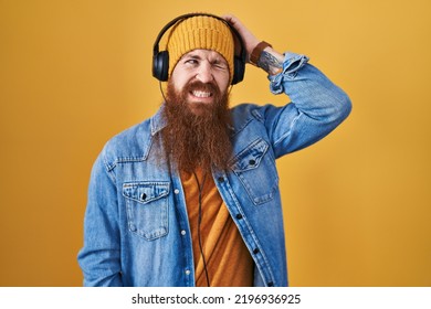 Caucasian Man With Long Beard Listening To Music Using Headphones Confuse And Wondering About Question. Uncertain With Doubt, Thinking With Hand On Head. Pensive Concept. 